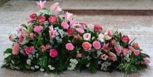 dessus de cercueil avec roses roses et fleurs roses pris de côté