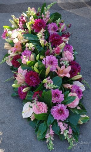 dessus de cercueil avec fleurs roses et violettes pris de devant